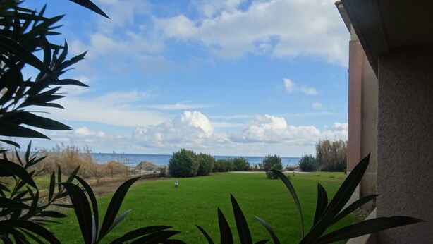 A view from a balcony overlooking a green lawn and a body of water. - la Castagna (San-Nicolao)