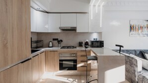 Une cuisine moderne avec des meubles en bois, un four encastré et un plan de travail équipé de divers appareils électroménagers.