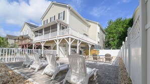 Une maison à deux étages avec un balcon, un espace extérieur aménagé avec des chaises et une clôture blanche.