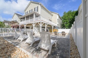 A two-story house with a balcony, outdoor seating area with chairs, and a white fence.