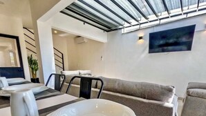 Un salon moderne comprenant un coin repas, un canapé et un téléviseur fixé au mur.