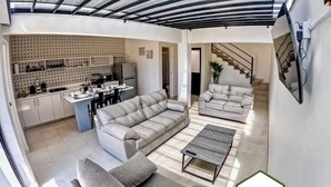 Un salon moderne comprenant un canapé, une table basse et un coin cuisine avec une table à manger et des chaises.