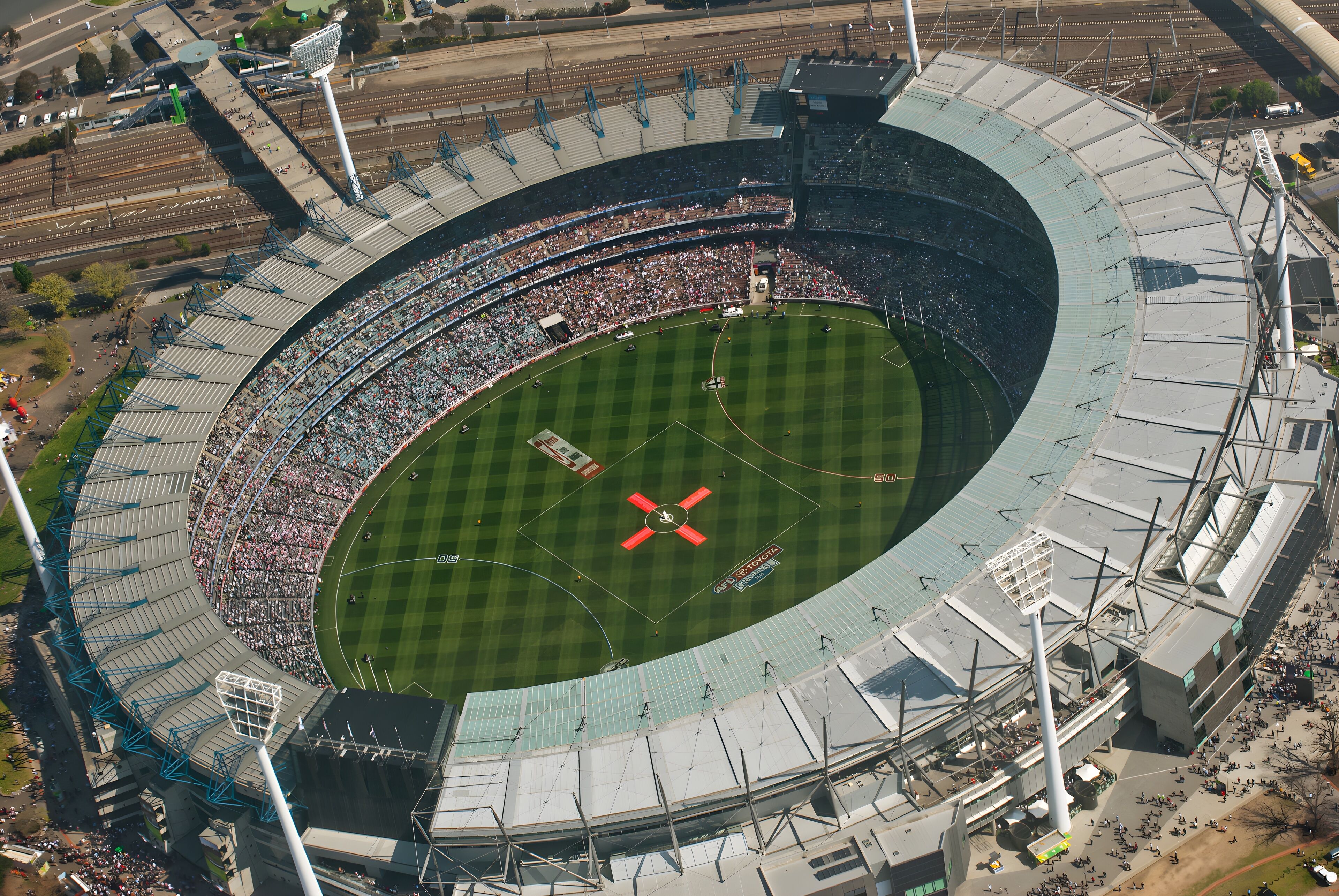 A large stadium with multiple tiers of seating, a central field, and a prominent tower structure.
