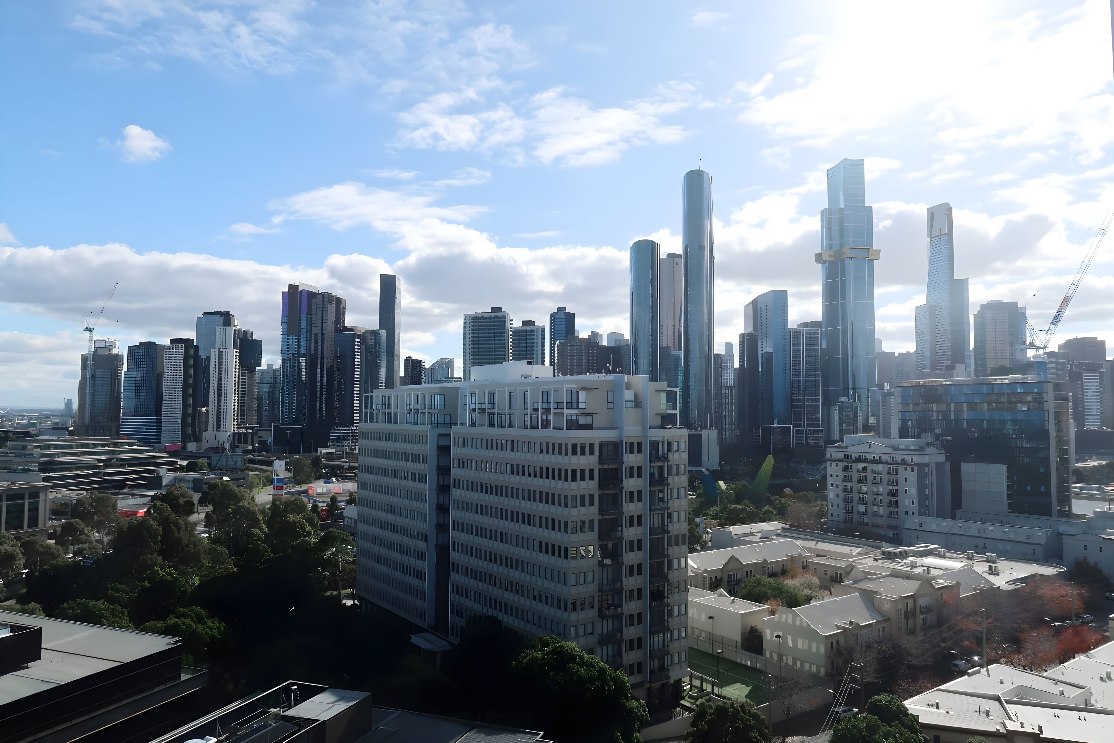 A city skyline with modern high-rise buildings, including a prominent cylindrical skyscraper.
