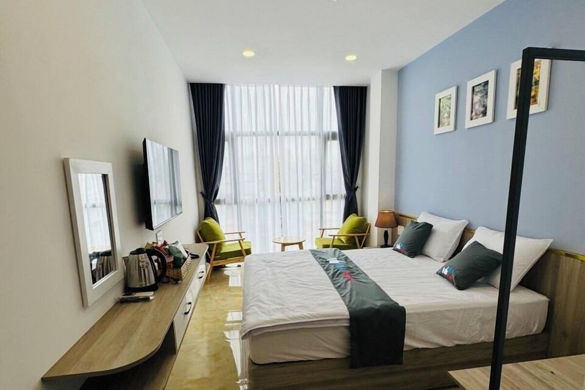 A modern hotel room with a large bed, a desk, a chair, and a TV.