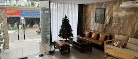 Un moderno vestíbulo de hotel con entrada de cristal, un árbol de Navidad, sofás de cuero y una pared de mármol.