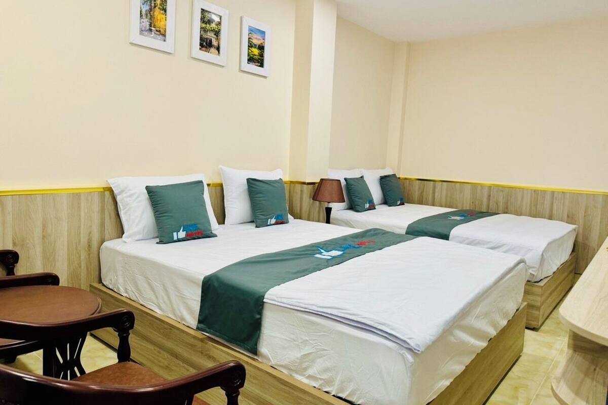 A hotel room with two beds, a wooden headboard, a small table, and a chair.