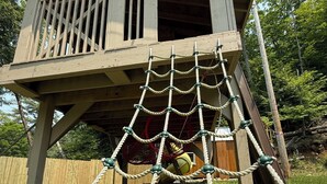 A wooden playhouse with a rope swing and a net. - Spectacular kid friendly home 2 minutes to Luzerne beach, 10min to Lake George! (Lake Luzerne)