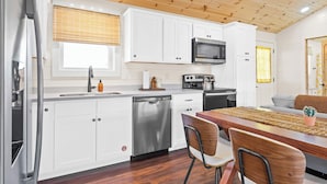 Una cocina moderna con armarios blancos, electrodomésticos de acero inoxidable y techo de madera.