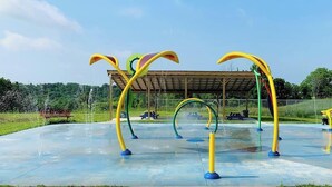 An outdoor playground with colorful climbing structures and a covered seating area.