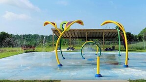 Un patio de juegos exterior con estructuras de escalada coloridas y una zona de estar cubierta.