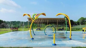 An outdoor playground with colorful climbing structures and a covered seating area.