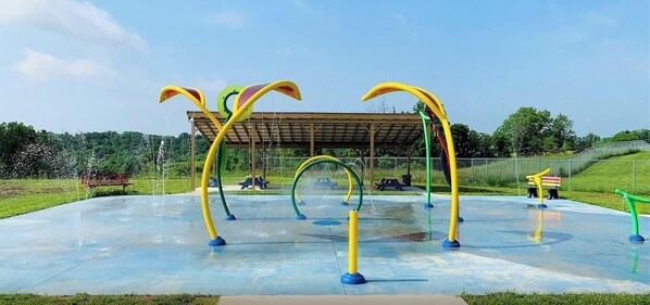 An outdoor playground with colorful climbing structures and a covered seating area.