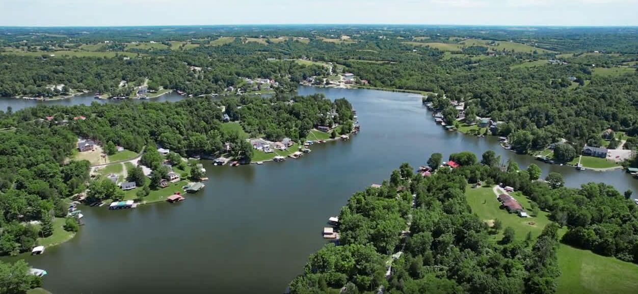 Luchtbeeld van een landgoed aan een meer, met meerdere vakantiehuisjes en een steiger.