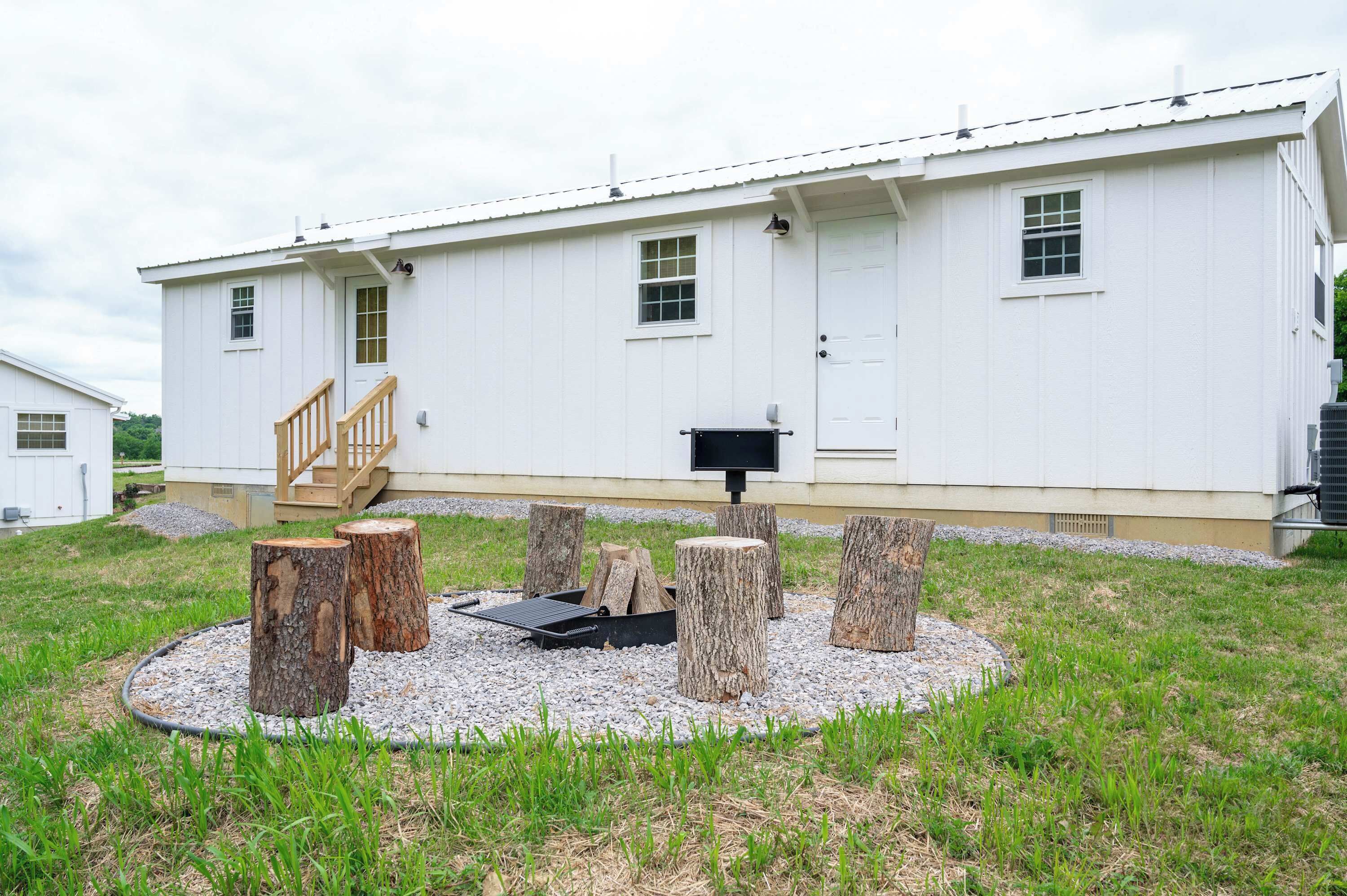 A white building with a wooden staircase, a black mailbox, and tree stumps arranged in a circle.