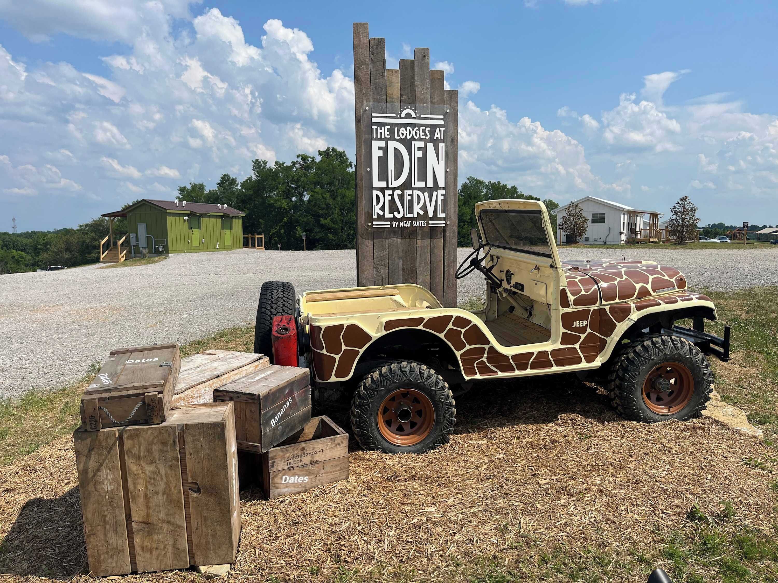 Een Jeep geparkeerd voor een bord waarop staat: The Lodges at Eden Reserve by Neat Suites.
