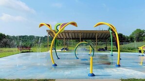 An outdoor playground with colorful climbing structures and a covered seating area.