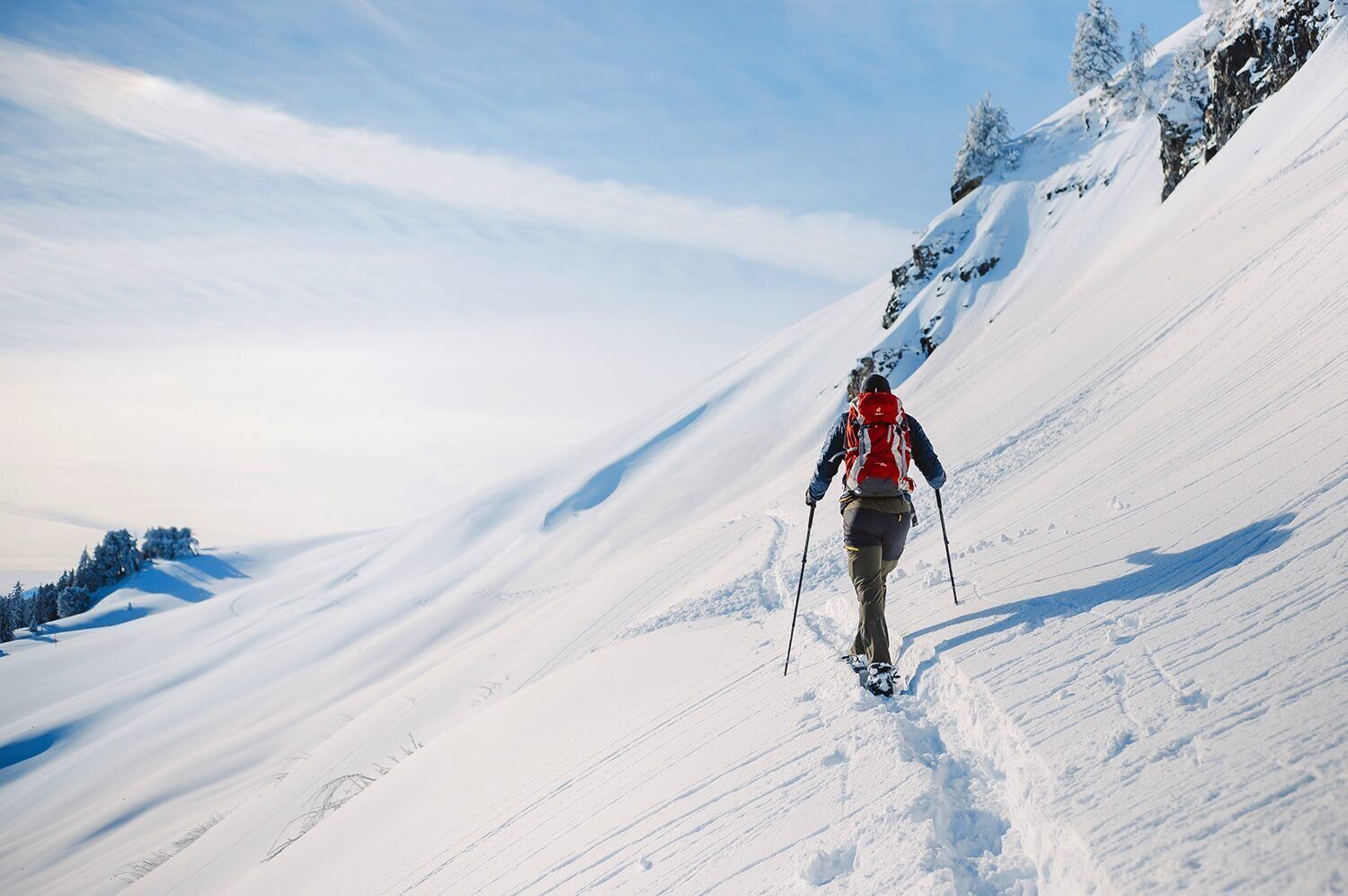 Una persona caminando por un sendero nevado en la montaña.