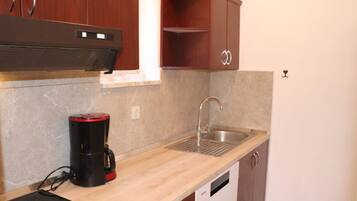 A compact kitchen with a built-in stove, a coffee maker, a sink, and wooden cabinets.
