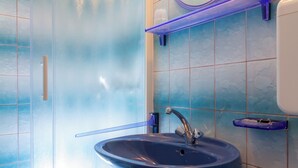 Une salle de bain avec une douche à parois de verre, un lavabo sur colonne, un miroir et un porte-savon.