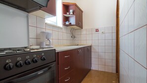 Une cuisine équipée d’une cuisinière, d’un four et de meubles de rangement en bois.