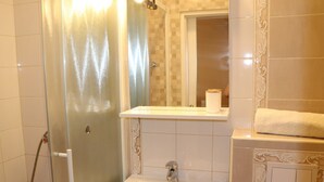 A bathroom with a glass shower enclosure, a sink, a mirror, and a towel on the counter. - Apartment mit Meerblick (Barbat)