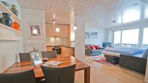 A modern apartment with a dining area, kitchen, and living space. - Apartment Hirle (Zermatt)