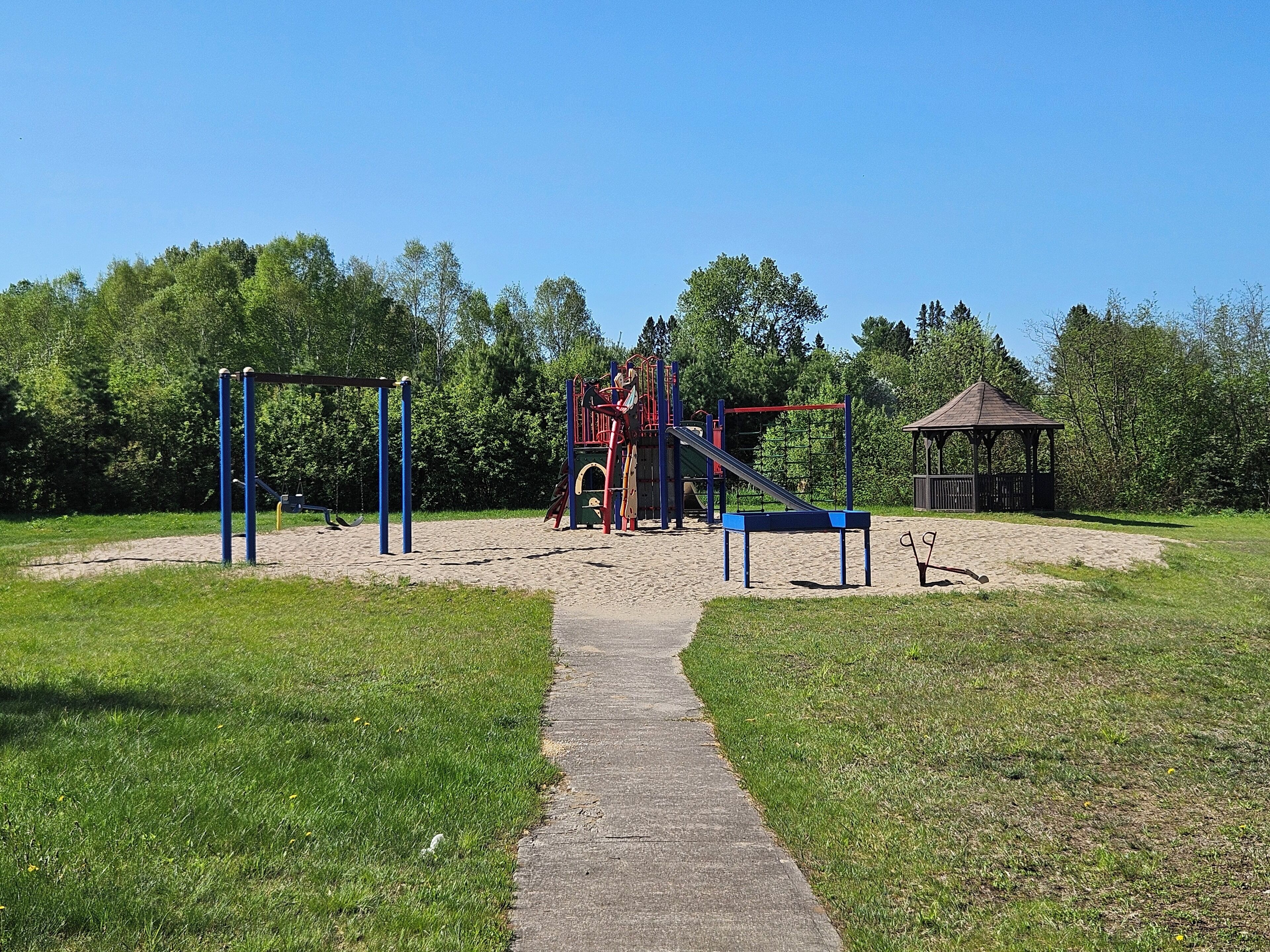 Ein Spielplatz mit Rutsche, Klettergeräten und einer Laube.