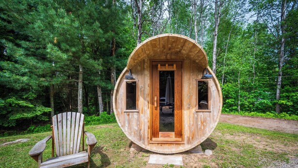 A wooden cabin with a circular design, a door, and two windows. - Cozy Family-Sized Cottage in Kearney - Hot Tub & Sauna 3 Min walk to Perry Lake (Kearney)