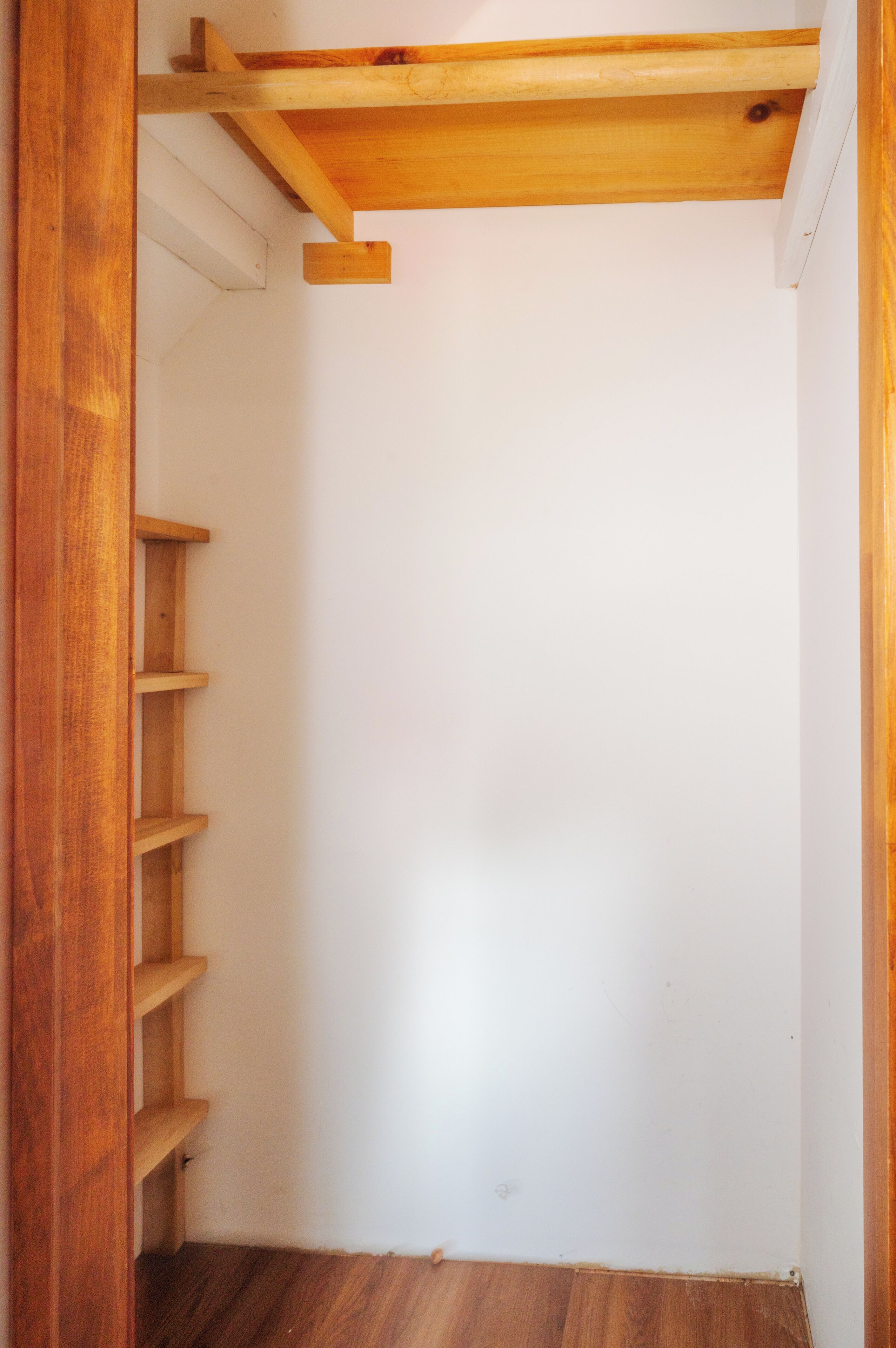 Een kamer met een houten plafond, een witte muur en een houten vloer.