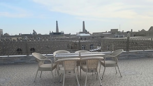 A rooftop terrace with a mosaic-tiled floor, wicker chairs, and a table. - Hotel Kuvonchoy Bonu (Khiva)