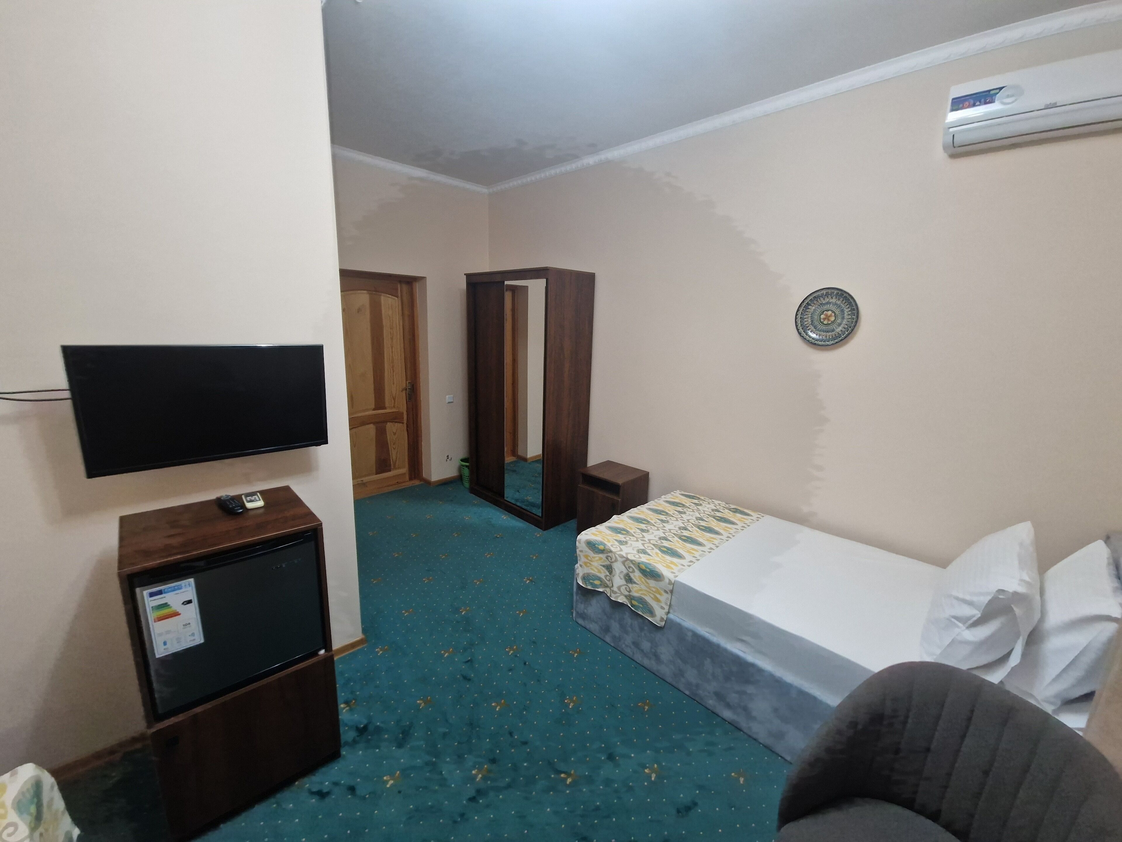 A hotel room with a bed, a TV, a small desk, and a wardrobe.
