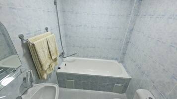 A bathroom with a bathtub, sink, toilet, and a green mat.
