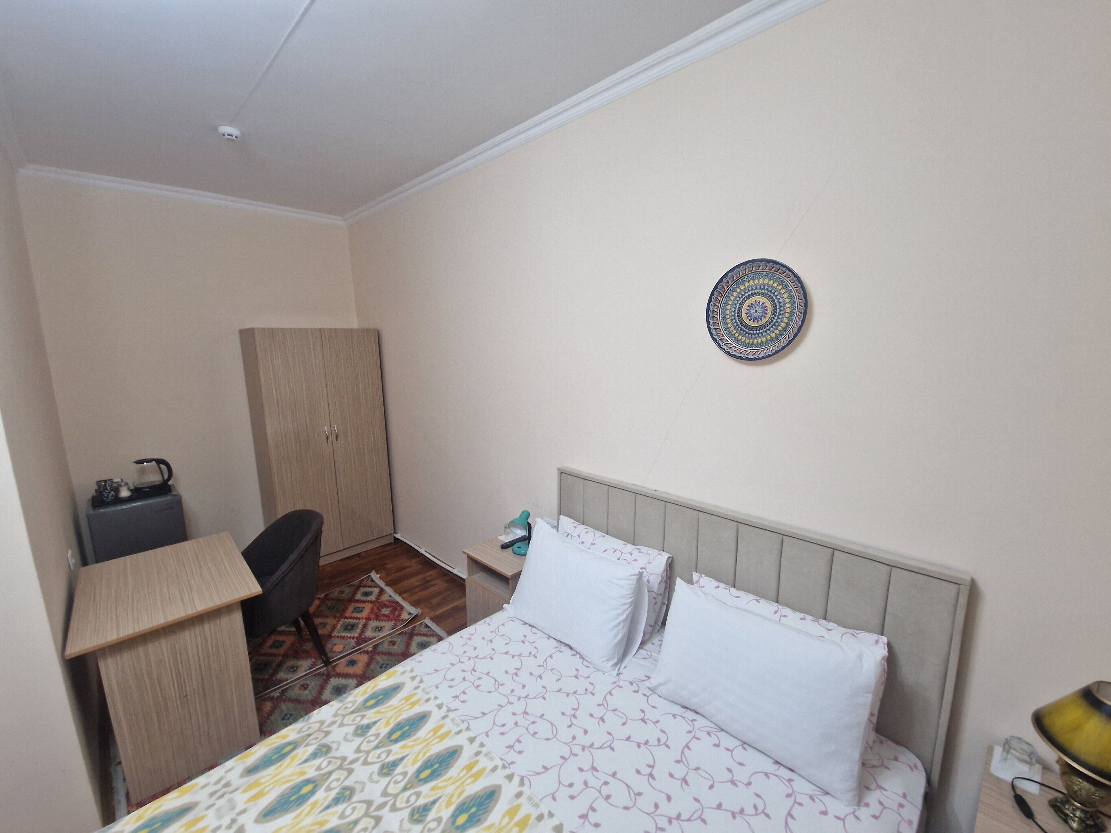 A hotel room with a bed, a desk, a chair, and a small cabinet.