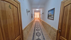 A hallway with wooden doors, a patterned carpet, and a framed picture on the wall. - Hotel Kuvonchoy Bonu (Khiva)