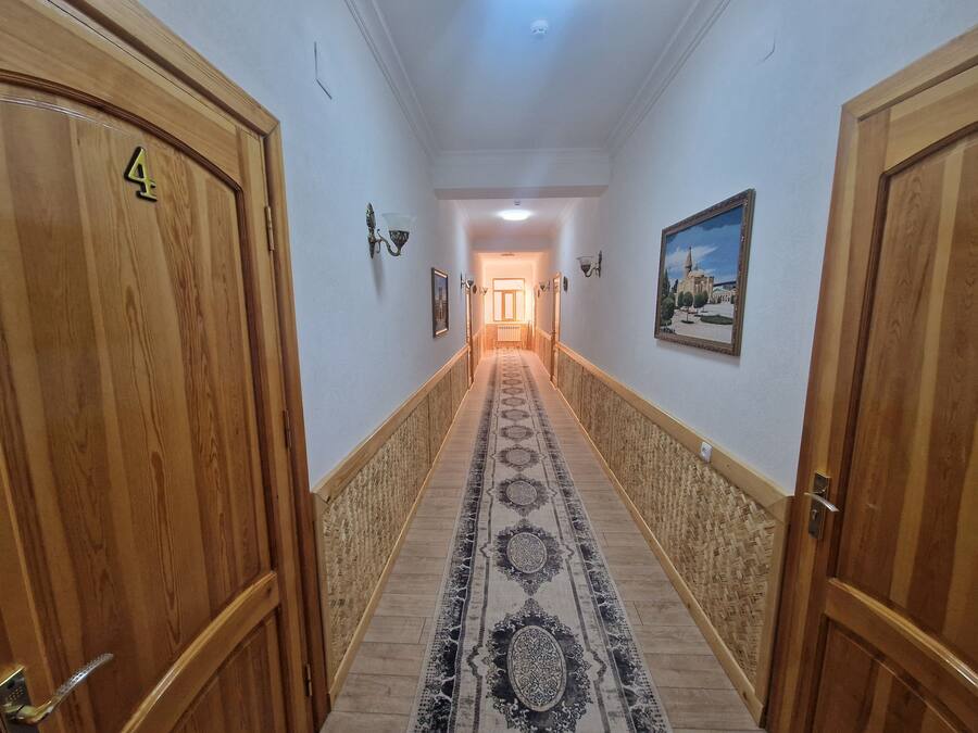 Um corredor com portas de madeira, carpete estampado e um quadro na parede.