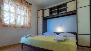 A neatly made bed with a yellow bedspread, a bedside lamp, and a window with curtains. - Apartment mit Meerblick (Barbat)