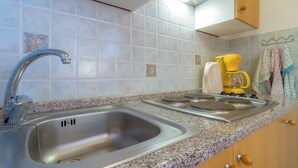 A kitchen with a stainless steel sink, a built-in stove, and a coffee maker. - Apartment mit Meerblick (Barbat)