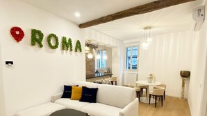 Ein modernes Wohnzimmer mit einem weißen Sofa, einem runden Tisch und einer Küche im Hintergrund.
