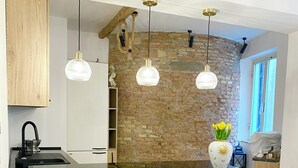 Eine moderne Küche mit schwarzem Arbeitsplatz, drei Barhocker und Pendelleuchten.