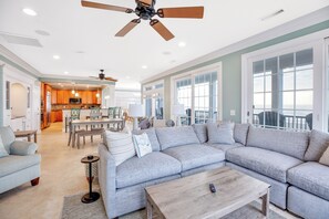 A spacious living area with a large grey sectional sofa, a wooden coffee table, and a ceiling fan. - Paradise Found: Oceanfront Luxury w/ Pool (Surfside Beach)