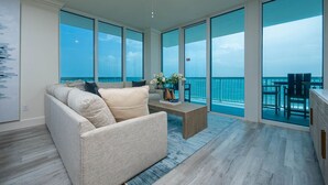 A spacious balcony with a view of the ocean, a comfortable seating area with a sofa and a coffee table, and a large window providing natural light. - Perdido Dunes Tower 9e 4 Bedroom Condo (Orange Beach)