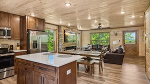 A spacious kitchen with wooden cabinets, a central island, and a stone fireplace.