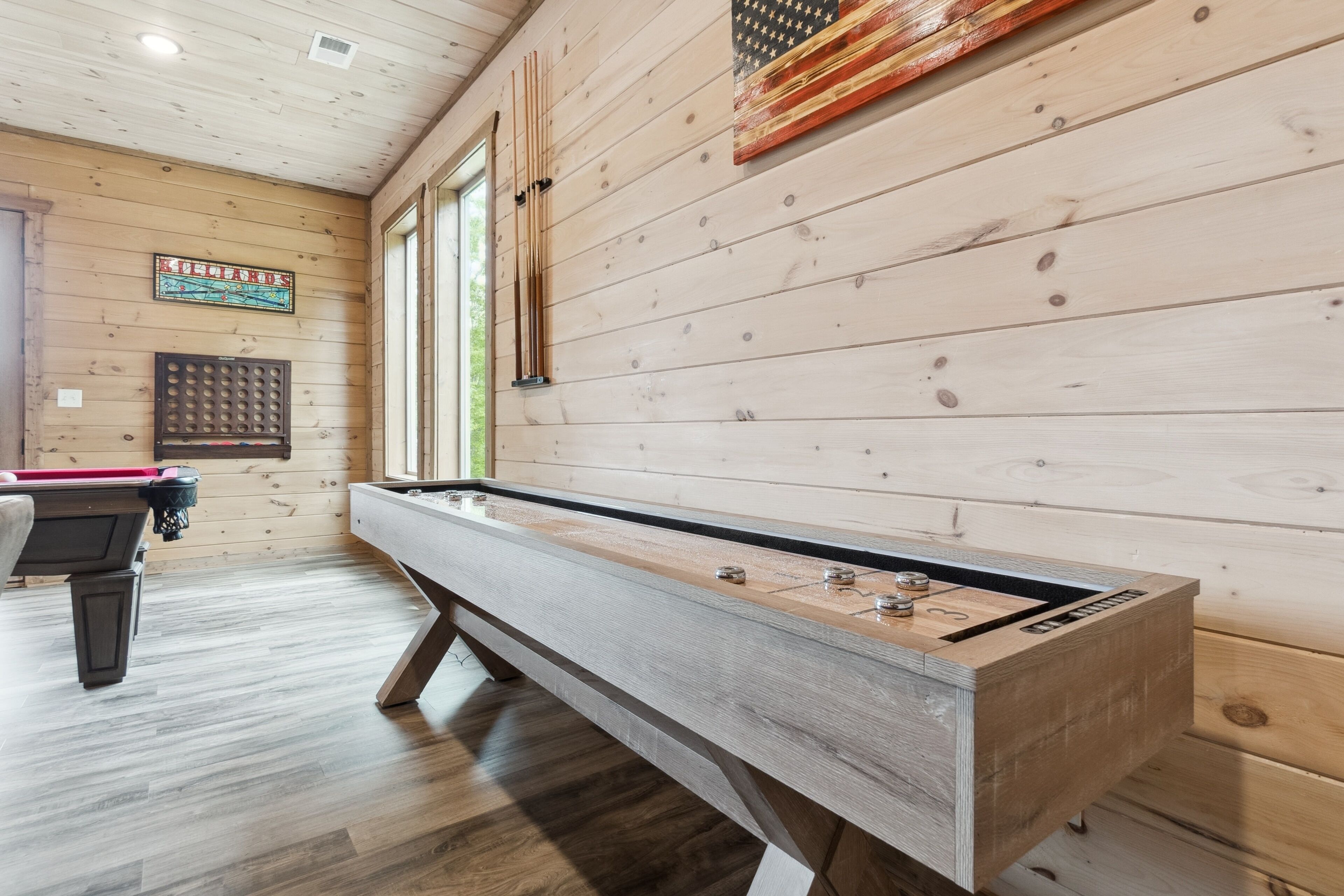 Een biljarttafel in een kamer met houten wanden en een raam.