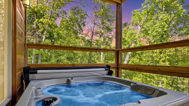 A hot tub with a wooden deck and a view of trees.