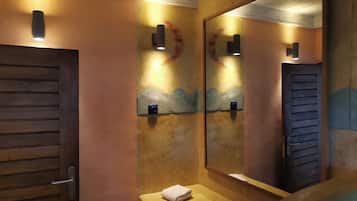 Simple, modern accommodations with a wooden door, bedside table, and large mirror.