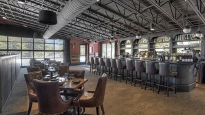 A bar area with high ceilings, exposed ductwork, and a bar counter with stools.