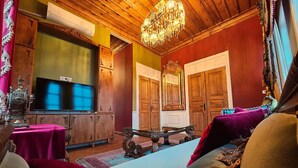 Ein traditionell eingerichteter Raum mit Holzwänden, einem Chandelier, einem Fernseher und einem großen Spiegel.