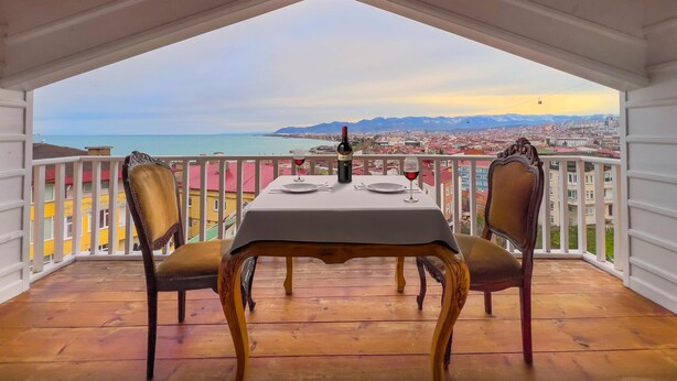 Ein Balkon mit Tisch für zwei Personen, mit Blick auf eine Küstenstadt.