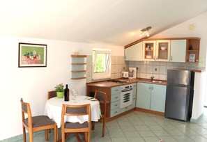 Eine kompakte Küche mit Essbereich, inklusive Tisch und Stühlen, einem Herd, einer Spüle und einem Kühlschrank.